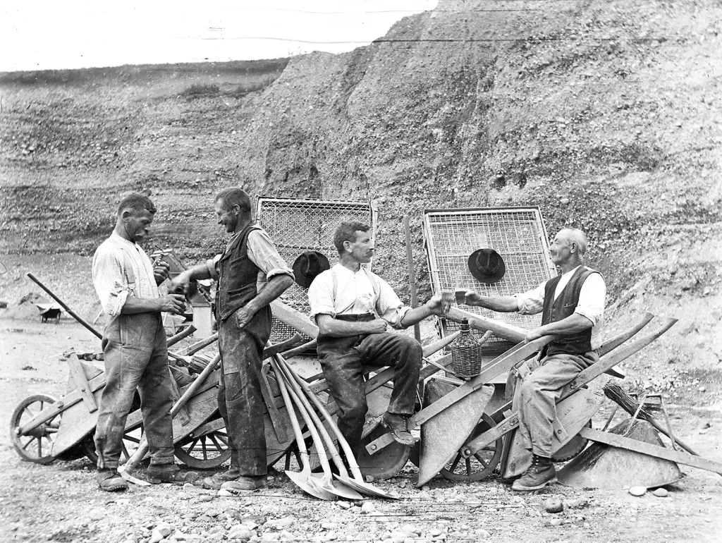Gruppe von Männern bei einer Arbeitspause mit Schoppen im Kieswerk